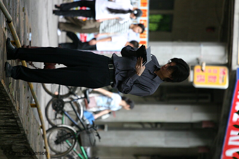 Photo of Man Standing, Reading on Sidewalk in China(3275)