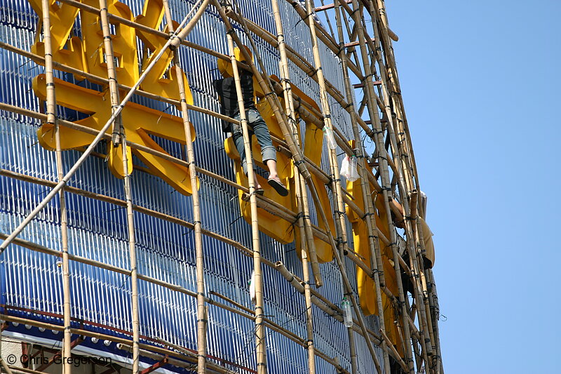 Photo of Worker Fixing Sign on Bamboo Scaffolding(3316)