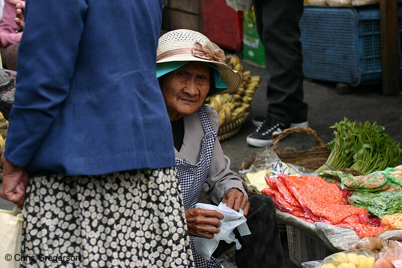 Photo of An Old Woman Selling Vegetables Peeks Through a Passerby in Baguio Public Market(5758)